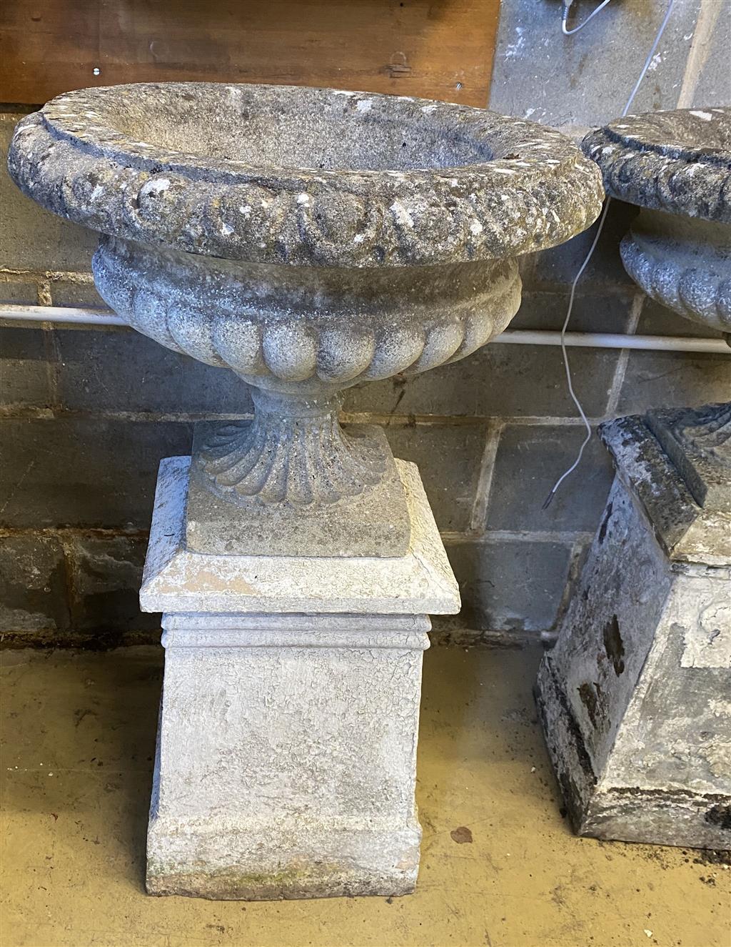 A pair of reconstituted stone campana garden urns and pedestals, 56cm diameter, height 99cm